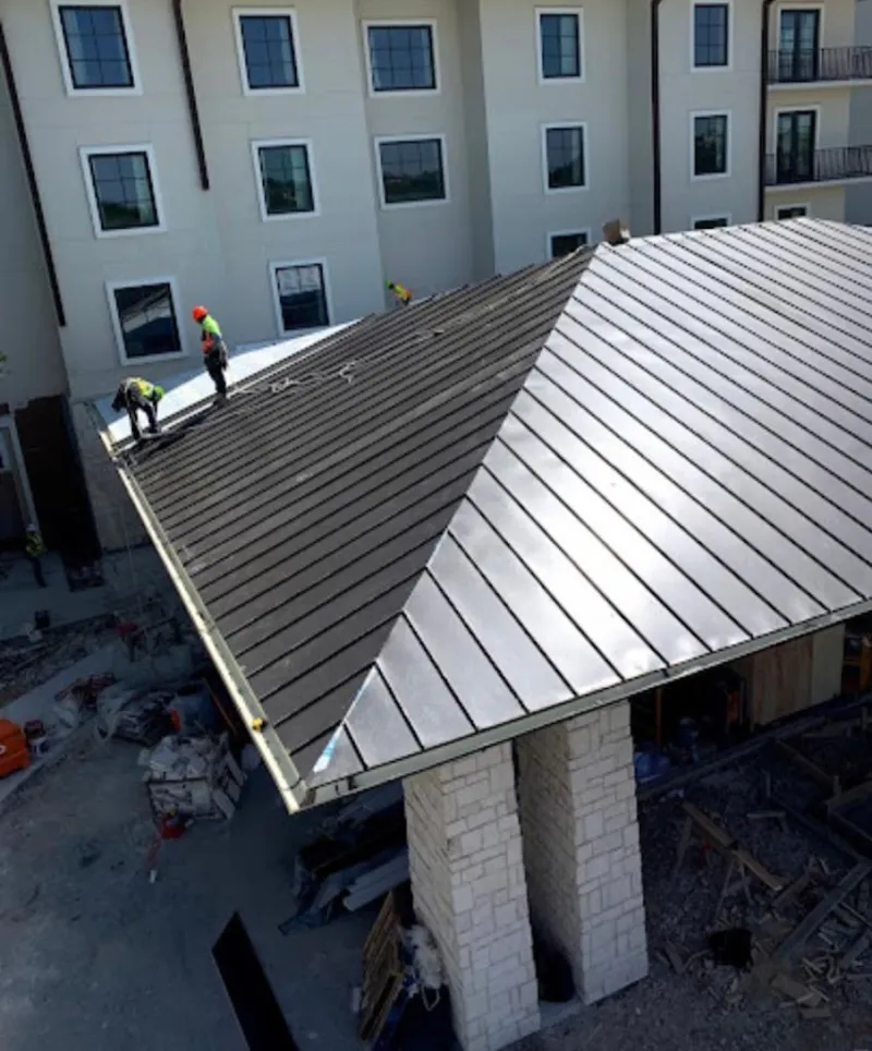 Crew installing standing seam metal roof panels on a commercial project in Covina